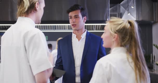 Menedżer Restauracji Mieszanej Rasy Męskiej Kuchni Trzymający Notatnik Rozmawiający Białą — Wideo stockowe