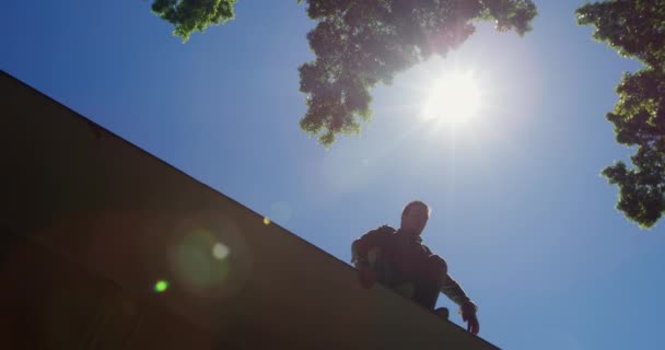 白人男性はカジュアルな服を着て 晴れた日に街の路上で駐車場を練習し 壁から飛び降り スローモーションで — ストック動画