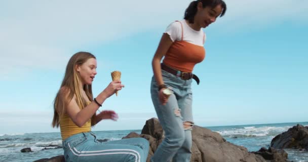 소녀는 해변에 바위에 소녀는 바위에서 뛰어내려 아이스크림을 동작으로 시간을 보내고 — 비디오