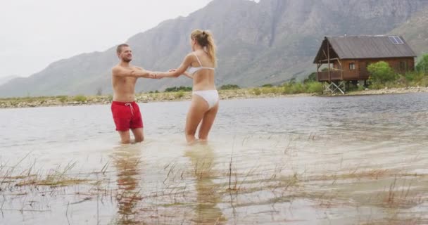 这对白种人夫妇穿着游泳衣 在湖中慢悠悠地跳舞 在登山途中玩得很开心 — 图库视频影像