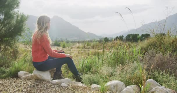 一个白种人女人 在登山途中玩得很开心 坐在岩石上 慢吞吞地欣赏风景 — 图库视频影像
