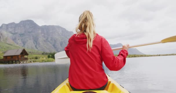 一个高加索女人的画像 她在登山途中玩得很开心 在湖上划船 拿着桨 看着相机 慢吞吞地笑着 — 图库视频影像