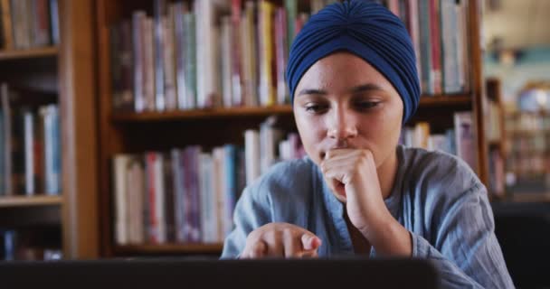 一名身穿蓝色头巾 在图书馆学习 使用笔记本电脑 身着休闲装 动作缓慢的亚洲女学生的近照 — 图库视频影像