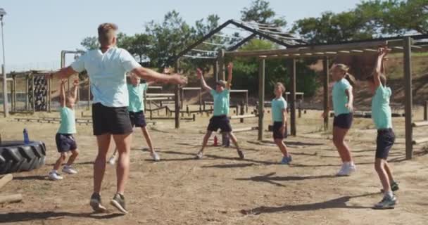 阳光灿烂的日子里 一群快乐的白人男孩女孩和一个白人男子教练在新兵训练营一起 穿着绿色T恤衫 慢吞吞地跳着舞 — 图库视频影像