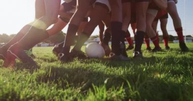 Rugby takımlarından oluşan iki genç erkek takım, yavaş çekimde bir ragbi maçında oyun sahasında çekişme yaratıyor.
