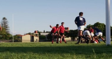 Rugby takımlarından oluşan iki genç erkek takım, ağır çekimde bir ragbi maçında takım elbiselerini giyiyorlar.