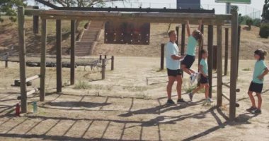 Güneşli bir günde Acemi Birliğindeki beyaz bir erkek koç, yeşil t-shirtler giyen maymunu ağır çekimde yeşil tişörtler giyer.