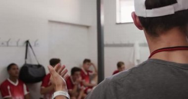 Kafkasyalı bir erkek rugby koçunun soyunma odasında çok ırklı rugby oyuncularından oluşan genç bir erkek takımla konuşarak, oturarak ve dinleyerek...