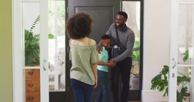 Karışık ırk ailesi evde eğleniyor, bir adam eve dönüyor, eşi ve oğluyla, karantina altındaki sosyal uzaklık ve kendini izolasyonla selamlıyor Coronavirus covid19 salgını sırasında, ağır çekimde