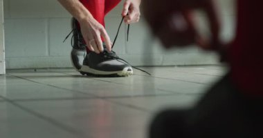 Kafkasyalı genç bir çim hokeyi oyuncusunun maçtan önce hazırlandığı soyunma odasında ayakkabısını yavaş çekimde bağladığı detaylar.