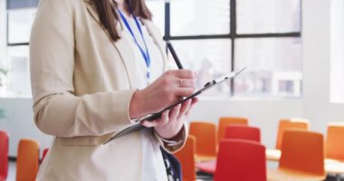 Kafkasyalı bir kadın iş dünyasının orta kesiminde gündelik modern bir ofiste çalışıyor, yavaş çekimde dizüstü bilgisayarda duruyor ve yazıyor.
