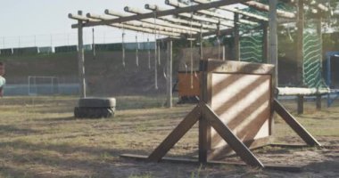 Güneşli bir günde acemi birliğindeki mutlu beyaz bir çocuğun yeşil tişörtlü, ağır çekimde duvardan tırmanması.