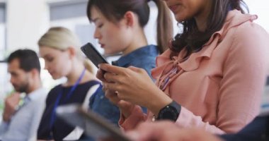 Bir iş konferansında seyirciler arasında sıraya dizilmiş, akıllı telefonları ve dizüstü bilgisayarları yavaş çekimde kullanan çok ırklı yaratıcı insanların yan görüntüsü