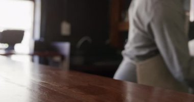 Beyaz önlüklü bir adamın, küçük bir birahanede çalışırken, bira servisi yaparken, ağır çekimde, ahşap bir bara koyarken..