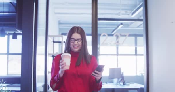 一个白人女商人在现代办公室的走廊里走着 喝着外卖咖啡 用智能手机 面带微笑 这些都是她的近景 — 图库视频影像