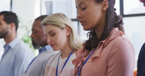 Vue latérale d'une entreprise féminine mixte créative assise dans le public lors d'une conférence d'affaires, écoutant et pensant, avec des collègues assis à côté d'elle au ralenti 