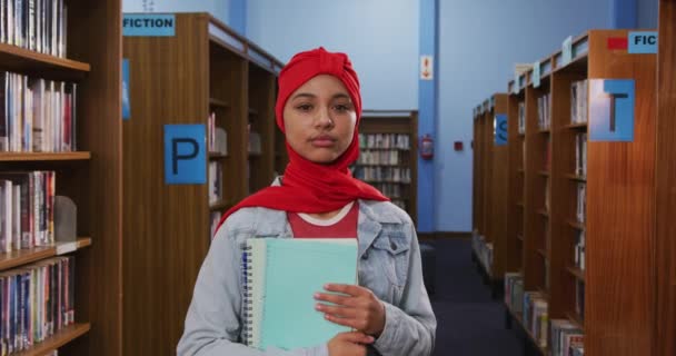 Portret Uśmiechniętej Azjatki Czerwonym Hidżabie Studiującej Bibliotece Patrzącej Kamerę Trzymającej — Wideo stockowe