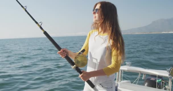 遅い動きで 晴れた日に 釣りロッドを保持し ボートで彼女の時間を楽しんで 十代の白人の女の子の側のビュー — ストック動画