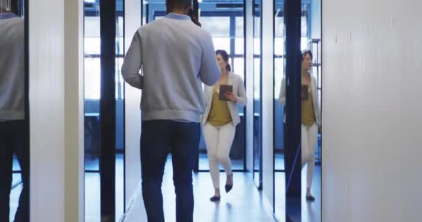 Vue de face d'une entreprise féminine asiatique marche créative dans le couloir d'un bureau moderne, sautant et célébrant le succès, portant un dossier, avec des collègues marchant à côté d'elle 