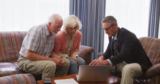 上了年纪的白种人夫妇呆在家里 坐在沙发上 与一位穿着漂亮的白种人交谈 在笔记本电脑的电脑屏幕上解释他们的数据 — 图库视频影像