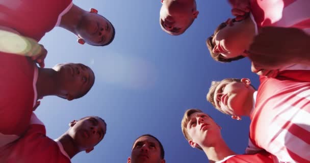 低视角抬头看一队年轻的多民族男子橄榄球队 他们穿着队服 拥抱着彼此 慢吞吞地交谈 — 图库视频影像