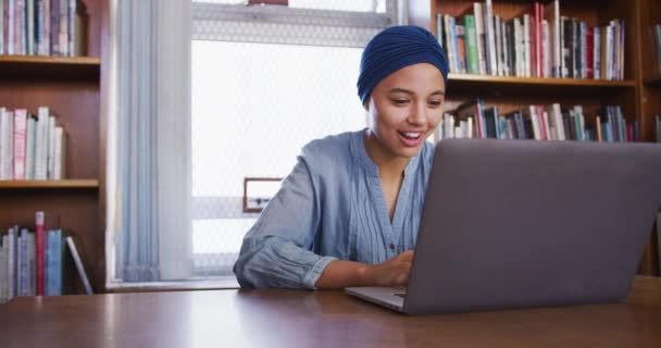 Estudante Asiática Feliz Vestindo Hijab Azul Estudando Uma Biblioteca Sentado — Vídeo de Stock