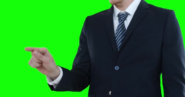 白いシャツとスーツを着た男の真ん中のセクションでは 腕を上げて彼の前に手を出し 緑の背景に仮想対話型スクリーンに触れる — ストック動画