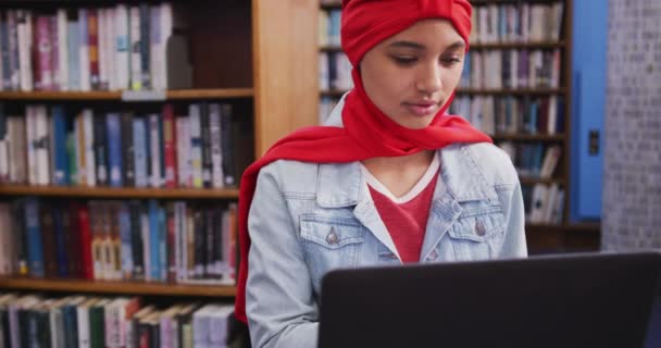 Студентка Азиатка Красном Хиджабе Учится Библиотеке Сидит Пользуется Ноутбуком Одета — стоковое видео