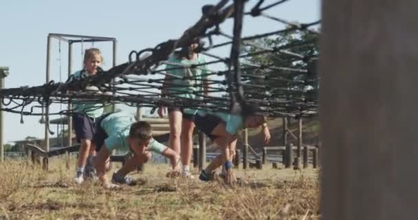 阳光灿烂的日子里 一群快乐的白人男孩和女孩在新兵训练营里 穿着绿色T恤衫 脚踏着四只鞋 慢吞吞地在网下走着 — 图库视频影像