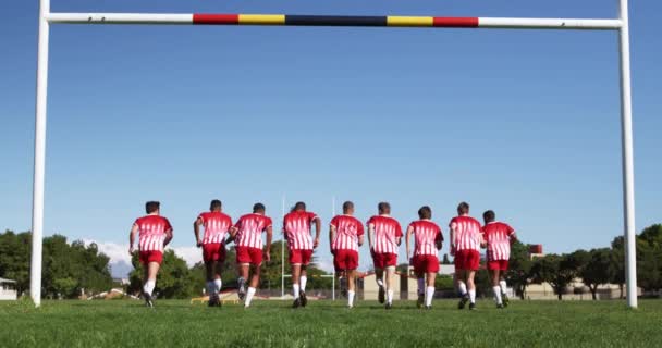 青少年多种族男子橄榄球队的后视镜 他们身穿红白相间的队服 在运动场上训练 慢镜头奔跑 — 图库视频影像