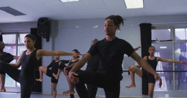 混血的现代舞男舞者身穿黑色衣服 站在一群适合的男女舞者面前 抬起腿 慢慢地伸出手来 — 图库视频影像