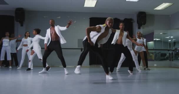 明るいスタジオでダンスクラス中にダンスルーチンを練習白い衣装を身に着けているフィットの男性と女性の現代ダンサーの多民族グループは 彼らの動きを同期させ スローモーションで — ストック動画