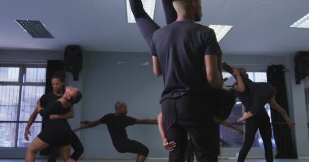 在明亮的演播室里 身穿黑色服装的现代男女舞者在舞蹈课上表演舞蹈 男人们把女人倒立着 动作缓慢 — 图库视频影像