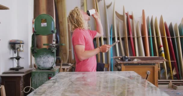 Καυκάσιος Κατασκευαστής Ιστιοσανίδων Μακριά Ξανθά Μαλλιά Στο Στούντιό Του Πίνοντας — Αρχείο Βίντεο