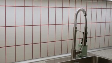Kırmızı çizgileri olan ince fayanslardan yapılmış bir mutfağın içi. Büyük bir lavabo ve geniş bir alan..