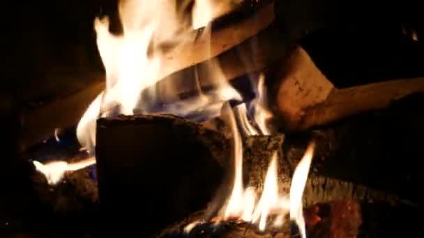 Photographiez un feu lumineux et saturé. Feu dans la cheminée, chaleur. Brûler des planches sur un fond sombre .