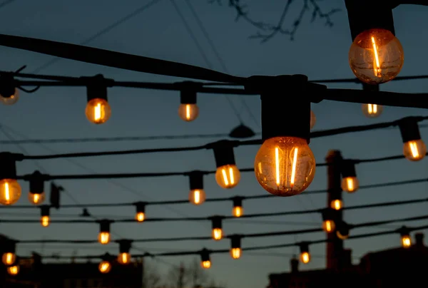 Лампочки Против Вечернего Голубого Неба Фонари Светятся Приятным Теплым Желтым — стоковое фото