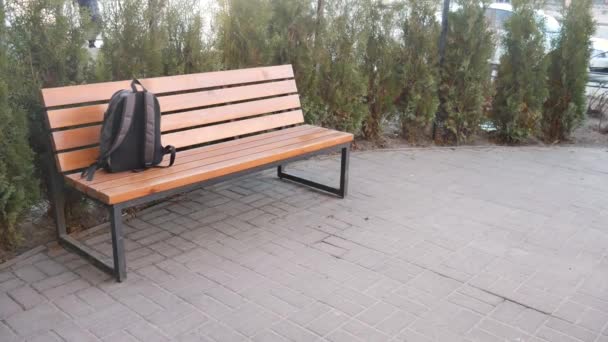 Een verloren rugzak liggend op een bankje in het park. — Stockvideo