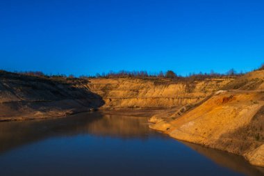 Nehir, göl ve dağ güzel sarı turuncu bir günbatımının arka planına karşı. Ormanlara ve dağlara karşı güzel, doğal gün batımı.