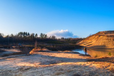 Nehir, göl ve dağ güzel sarı turuncu bir günbatımının arka planına karşı. Ormanlara ve dağlara karşı güzel, doğal gün batımı.