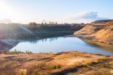 Nehir, göl ve dağ güzel sarı turuncu bir günbatımının arka planına karşı. Ormanlara ve dağlara karşı güzel, doğal gün batımı.