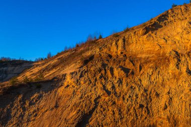 Mavi bulutsuz gökyüzüne karşı büyük kumlu bir dağ.