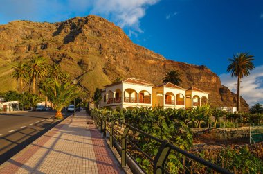 Beyaz bulutların üstünde mavi gökyüzü, Playa Ingles, La Gomera Adası, İspanya ile volkanik siyah kum plajı üzerinde taşlar kayalar