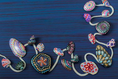 El-boyalı taşlar ve kabukları ile mavi ahşap arka plan 