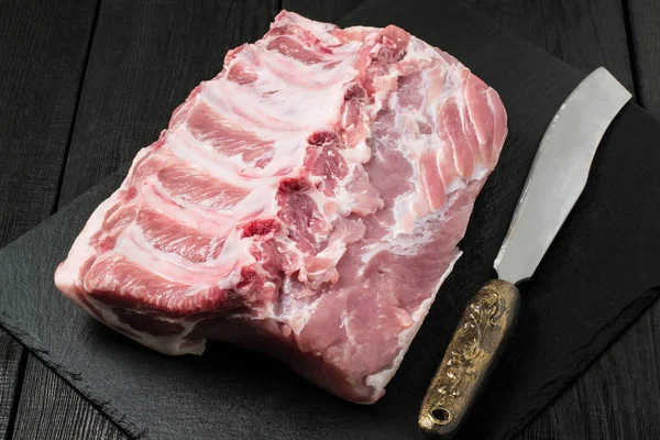 Filet de porc cru et couteau sur plaque d'ardoise — Photo