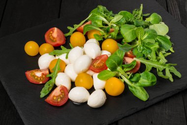 Mozzarella peyniri, domates ve farklı salata yaprakları 