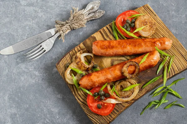 Жареные сосиски и овощи на деревянной тарелке — стоковое фото