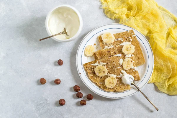 Panqueques rusos finos con crema agria, plátanos y avellanas — Foto de Stock