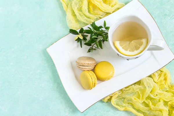 Yellow macaroon and tea with lemon in cup — Stock Photo, Image