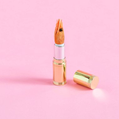 Tüp ruj ve karides pastel pembe bir arka plan üzerinde. Minimalist tarzı. Renk ve şekil yaratıcı bir fikir. Gıda ve moda Tema fanteziler